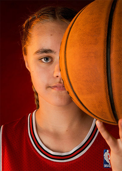 Jeune basketteuse en action avec son ballon pendant un shooting photo personnalisé sur le thème du sport