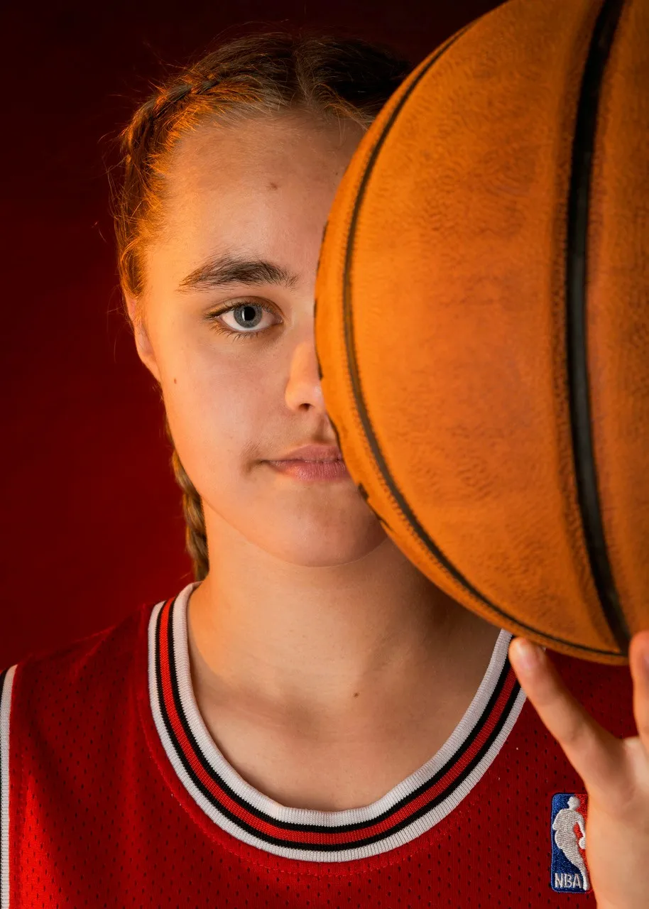 Jeune basketteuse en action avec son ballon pendant un shooting photo personnalisé sur le thème du sport